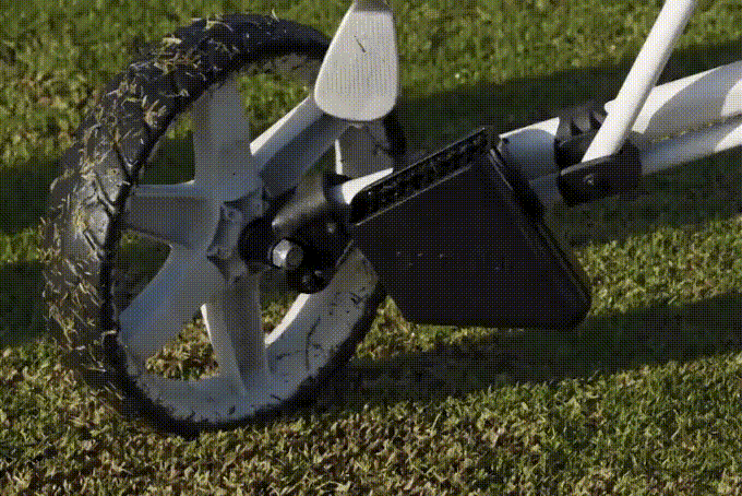 A Scrubi golf club cleaner, attached to a clicgear pushcart, being used to clean a dirty golf club.