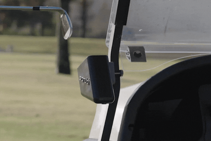 A Scrubi golf club cleaner being used to clean a ditry golf club, while the Scrubi is mounted on a golf cart.
